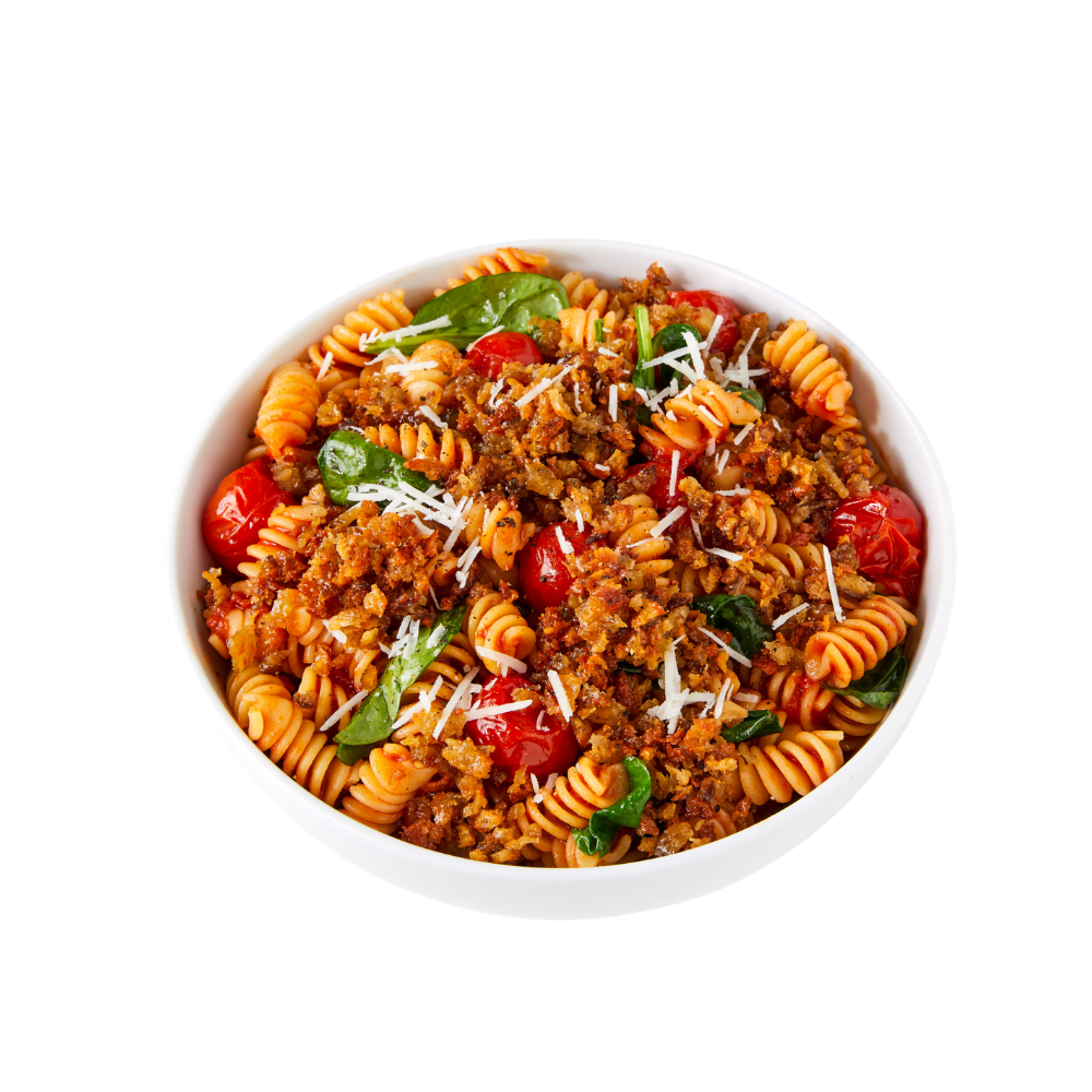 A bowl of rotini pasta topped with Blackbird Italian sausage seitan crumbles